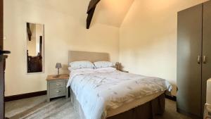 a bedroom with a bed with a nightstand and a mirror at Curry Mallet Cottages in Taunton