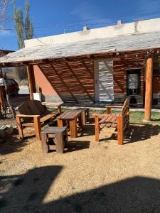 um grupo de mesas de piquenique e bancos em frente a um edifício em Cabaña Los Girasoles Cachi Salta em Cachí