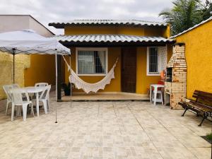 a patio with a hammock and a house at Casa Amarela de Praia in Maricá