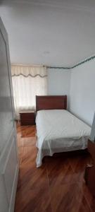 Schlafzimmer mit einem weißen Bett und Holzboden in der Unterkunft villa concha in Paipa