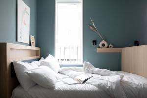 Un dormitorio con una cama blanca con dos libros. en Bob W Tower Hill Studios en Londres
