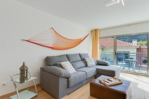 uma sala de estar com um sofá e uma rede de descanso na parede em Sunny Beach Machico Apartment by HR Madeira em Machico