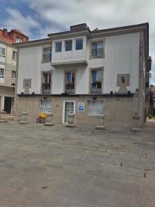 a large white building with windows on a street at A Parada do Camiño Albergue y habitaciones privadas in Padrón