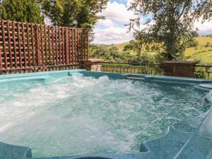 a hot tub with water in it in front of a fence at Hillside Lodge in Llandrindod Wells