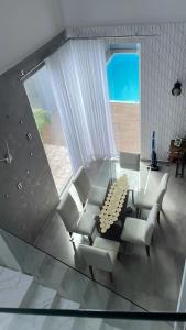 a living room with a glass table and white chairs at Sobrado com 3 quartos piscina 100m mar em matinhos in Matinhos