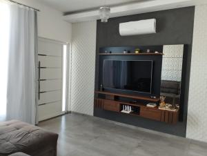 a living room with a television on a wall at Sobrado com 3 quartos piscina 100m mar em matinhos in Matinhos