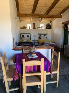 a dining room with a table and two beds at Cabaña Los Girasoles Cachi Salta in Cachí