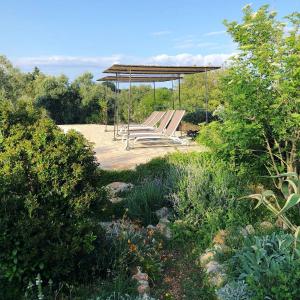 un parc avec des bancs et un auvent dans un jardin dans l'établissement Casa della Scrittrice, à Ostuni
