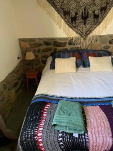 Una cama con dos almohadas y una manta. en Cabaña Los Girasoles Cachi Salta en Cachí