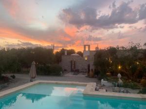 - une piscine en face d'une maison avec un coucher de soleil dans l'établissement Casa della Scrittrice, à Ostuni