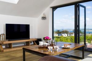 ein Wohnzimmer mit Tisch und Fernseher in der Unterkunft Cedar Lodge in Carbis Bay