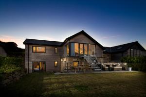 ein Haus mit Glastüren und einer Steinmauer in der Unterkunft Cedar Lodge in Carbis Bay