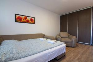 a bedroom with a bed and a chair at Sava centar-Stark Arena lux apartman Ema in Novi Beograd