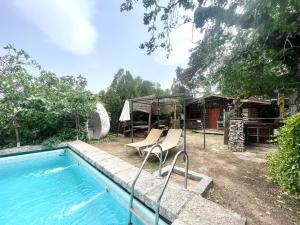 a pool with two chairs next to a house at Casa Fidelina IV Miraflores de la Sierra in Miraflores de la Sierra