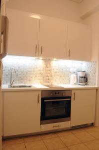 a kitchen with white cabinets and a sink at Sunset by the sea 2 in Loutraki