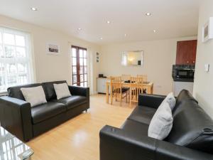 a living room with two black couches and a kitchen at Whistle Stop Apartment in Porthmadog
