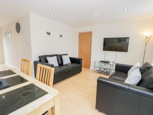 a living room with a black couch and a tv at Whistle Stop Apartment in Porthmadog