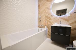 a bathroom with a tub and a sink and a mirror at Apartament 12 in Chojnice +13 photos