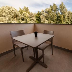 un tavolo bianco e sedie su un balcone con alberi di Castelli del Chianti a Gaiole in Chianti