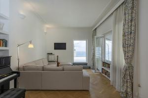 ein weißes Wohnzimmer mit einem Sofa und einem TV in der Unterkunft Attic with Amazing Seaview Terrace by Wonderful Italy in Genua