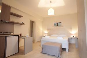 a bedroom with a white bed and a kitchen at Asterias in Skiros