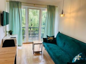 a living room with a green couch and a window at Apartamenty Bałtyckie in Sopot