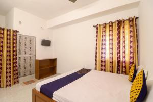 a bedroom with a bed and curtains and a tv at SPOT ON Hotel Om Kanha in Bilāspur