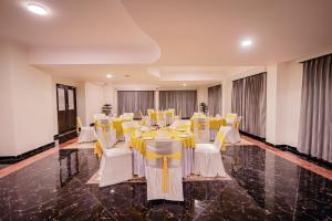 un salón de banquetes con mesas amarillas y sillas blancas en Regenta Resort MARS Valley View Shoghi, en Shimla