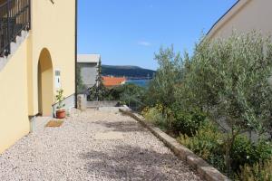 a walkway between two buildings with bushes and trees at Studio Lavanda in Kornić, Krk in Kornić