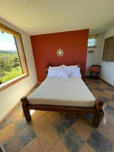 Chales Sitio dos Ventos في لافراس نوفاس: سرير كبير في غرفة مع نافذة كبيرة