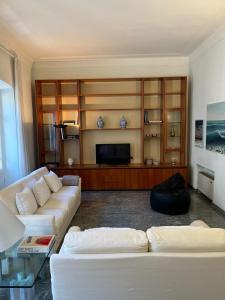 un soggiorno con 2 divani bianchi e una TV di Casa in Centro a Sanremo
