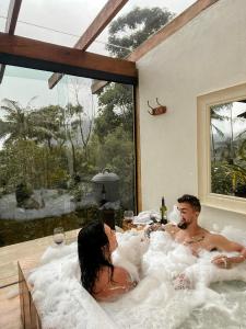 a man and a woman sitting in a bath tub at Chalés Paraty Real in Paraty