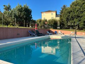 einen Pool mit Stühlen und Sonnenschirmen neben einem Haus in der Unterkunft La Filanda in Montalto delle Marche