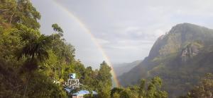 a rainbow in the mountains with a house and trees at Green Village in Ella