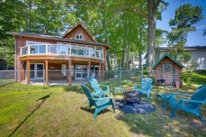 a house with chairs and a fire pit in the yard at Lakefront Cadillac Retreat with Sauna and Boating! in Cadillac
