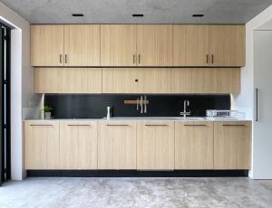 uma cozinha com armários de madeira e um lavatório em Luxury Urban Oasis with Garden and Private Studio em Londres