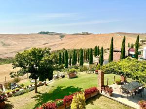 a garden with a table and chairs and trees at Podere Poggio Salto in Pienza