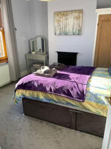 a bedroom with a bed with a purple comforter at Charming 2 double bed cottage style house in Bristol