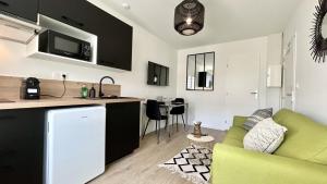 a living room with a green couch and a kitchen at L'Escale in Fort-Mahon-Plage
