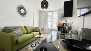 a living room with a green couch and a table at L'Escale in Fort-Mahon-Plage