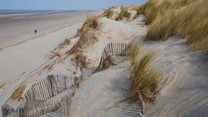 a fence on a sandy beach next to a beach at L'Escale in Fort-Mahon-Plage