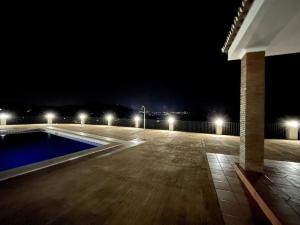 uma vista nocturna para uma piscina com luzes em Casa Rural Lomillas de Canca em Alora