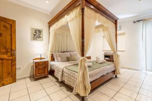 una camera da letto con letto a baldacchino e finestra di Maisonette filled with Maltese charm in the south of Malta a Marsaskala