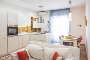 a living room with a white couch and a kitchen at Cozy flat with terrace at Trastevere train station in Rome