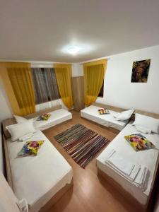 Habitación con 3 camas y cortinas amarillas. en Къща за гости "Холидей - Луковит" en Lukovit