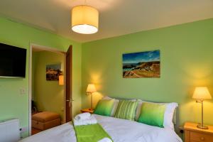 a green bedroom with a bed and a tv at Finest Retreats - Skylarks in Boscastle