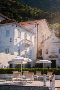 Heritage Grand Perast By Rixos في بيراتس: مجموعة من الكراسي والمظلات أمام المبنى