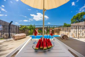a table with a plate of watermelon and wine glasses at Villa Cocoon - Vacation Home with Heated Pool & Garden in Bribir +37 photos