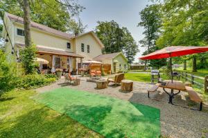 a patio with chairs and tables and an umbrella at Spacious Victorian Home quarter Mi to Holiday Valley! in Ellicottville