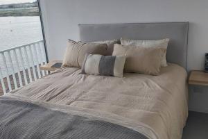 1 cama grande con almohadas y vistas al agua en Sueños del Lago Puertos/Escobar en Buenos Aires